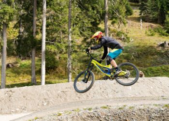 Lenzerheide, GR / Switzerland, - 12 October, 2019: downhill mountain biker jumping high and riding hard in Lenzerheide in the Swiss Alps
